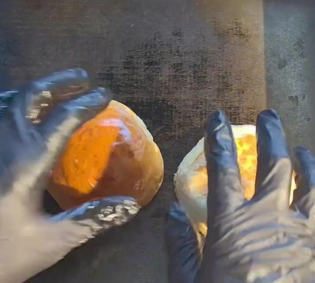 Ein rohes Rindfleisch-Patty brutzelt auf einer heißen Grillplatte.