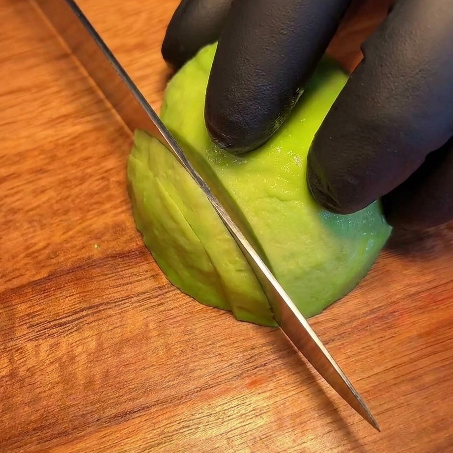 Gleichmäßige, frische Avocado-Scheiben ordentlich auf einem Holzbrett angeordnet.