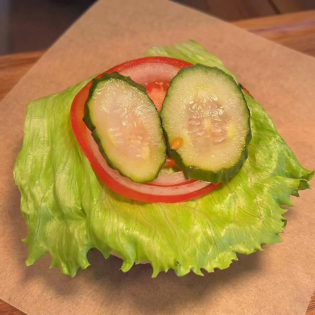Ein gegrilltes Rindfleisch-Pattie mit geschmolzenem Käse wird auf das Gemüse gelegt.
