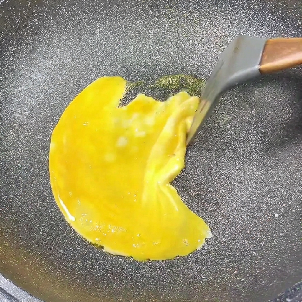 Ein Eipancake, der in einer Pfanne gart, während die Ränder zur Mitte gezogen werden.