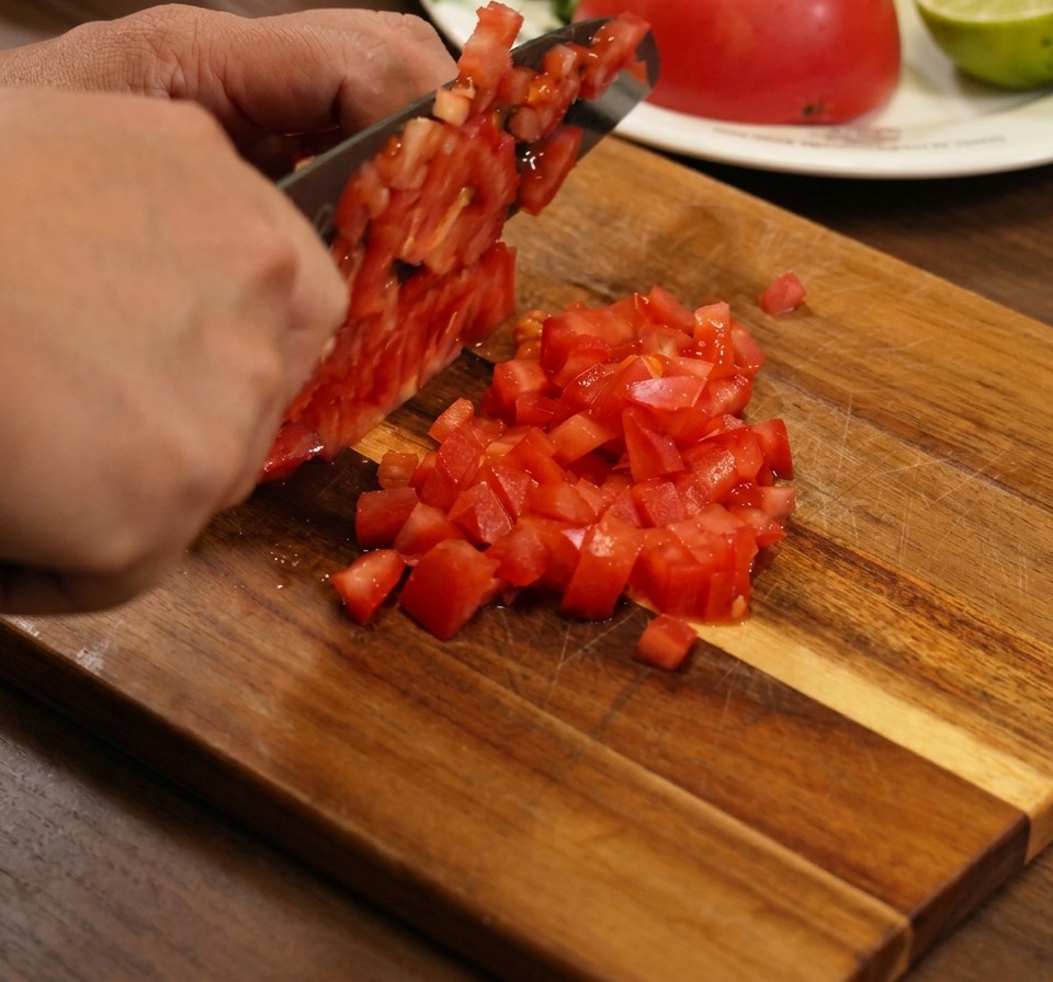 Nahaufnahme von frischen, gewürfelten Tomaten, roten Zwiebeln und Koriander, die in einer Schüssel vermischt werden.