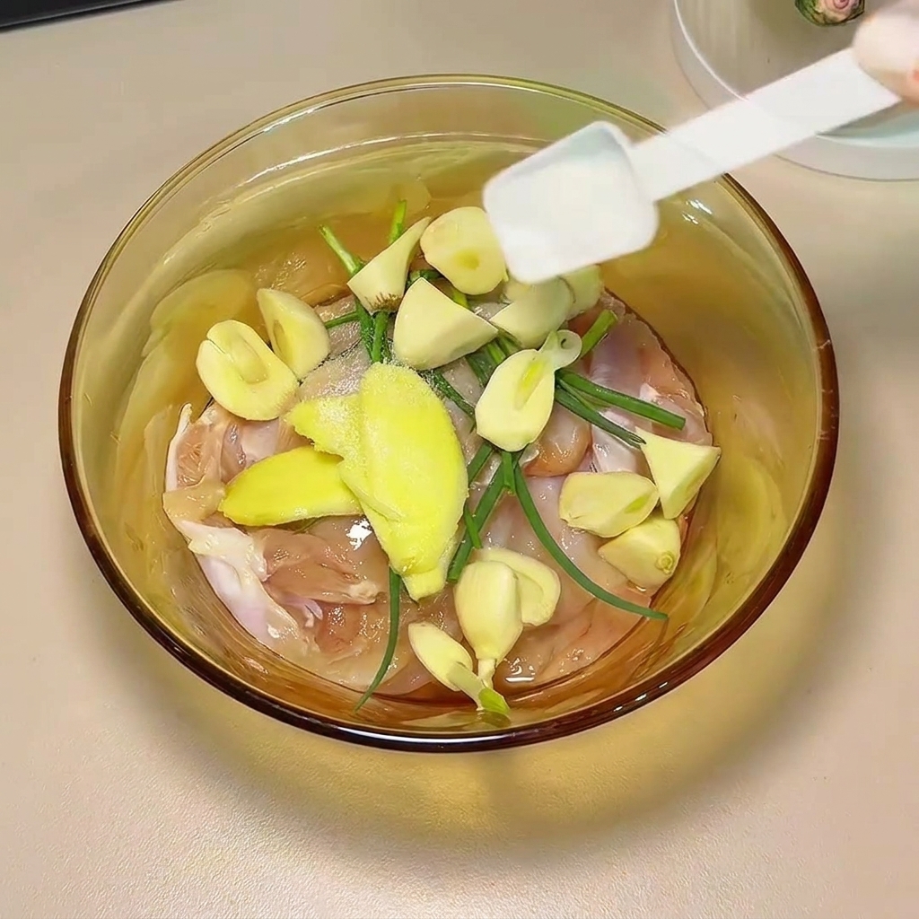 Sojasauce und Gewürze werden über die Hähnchenschenkel und Aromaten gegossen.