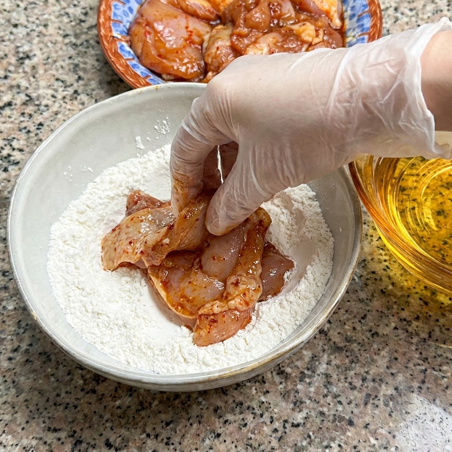 Ein Hähnchenschenkel wird in Mehl gewendet.