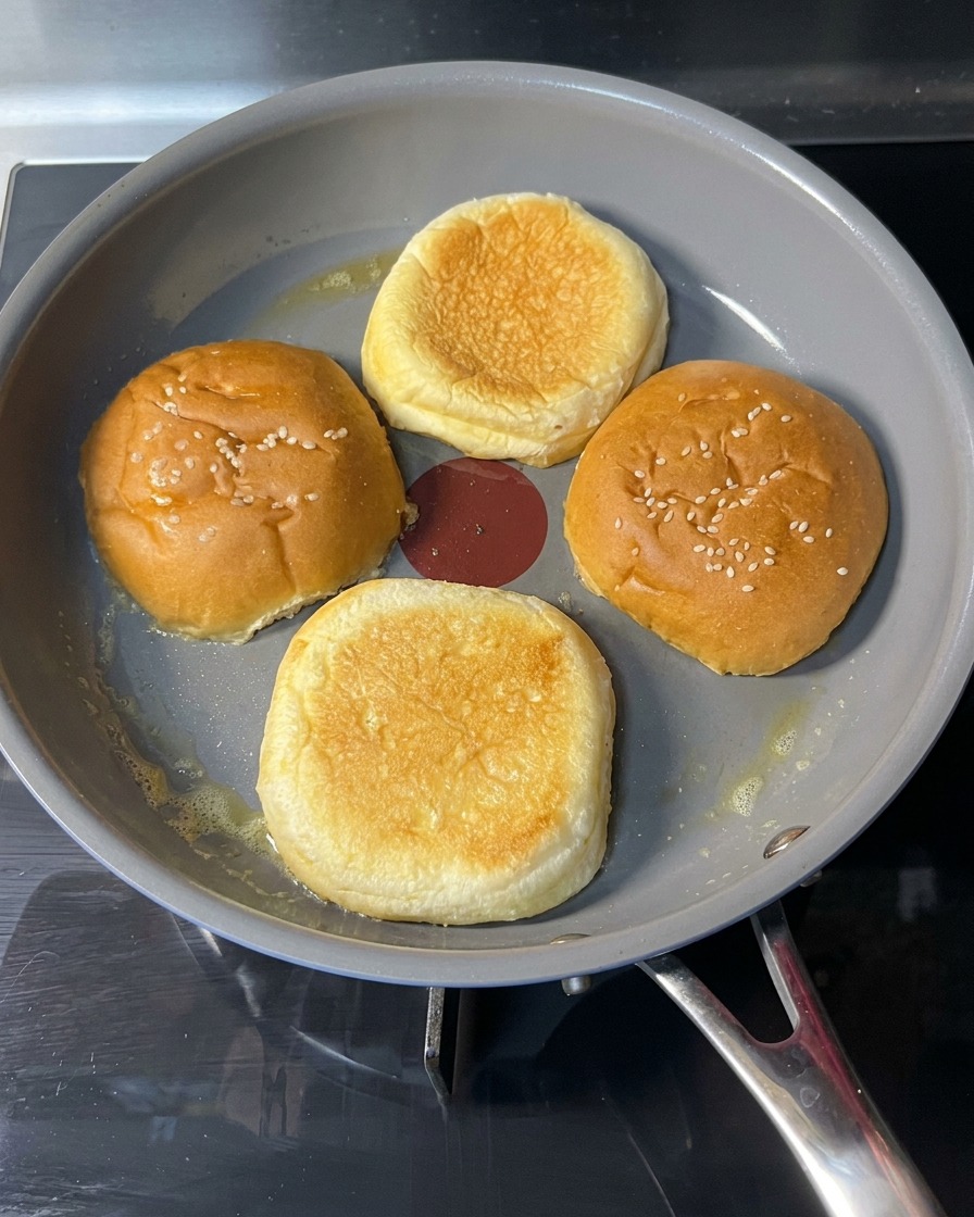 Ein geröstetes Brötchen wird in der Pfanne gewendet, um die goldbraune Seite zu zeigen.