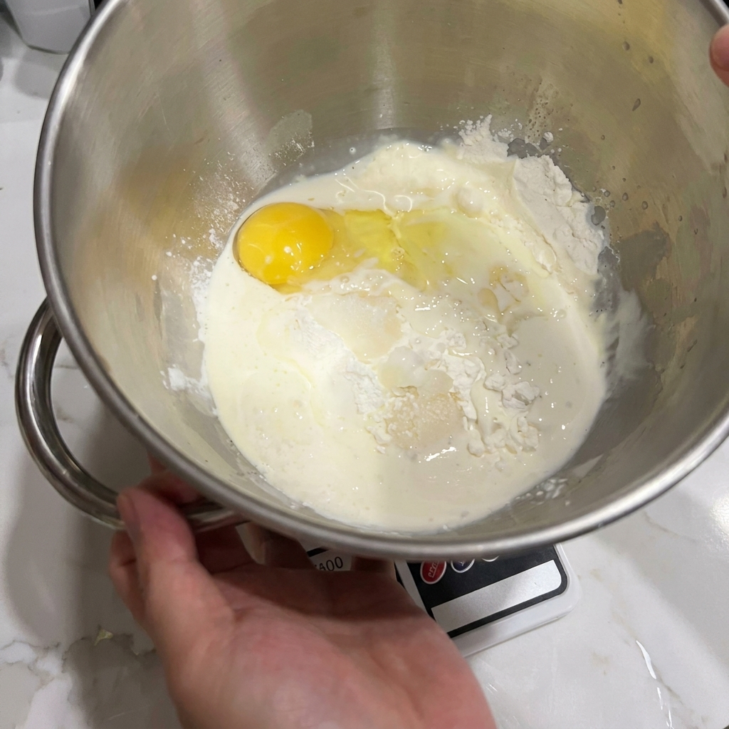 Eine Schüssel der Küchenmaschine mit Mehl, einem Ei und Milch.
