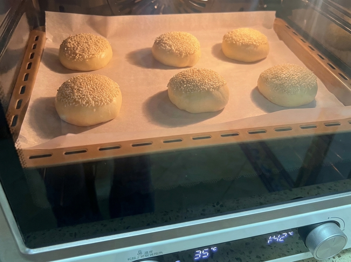Ein Backblech mit Sesam-Teigballen im Ofen.