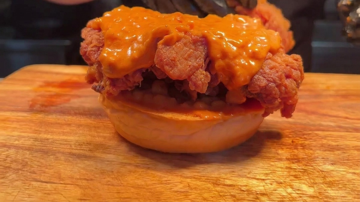 Ein zweites Patty wird auf das erste Hähnchenstück geschichtet.