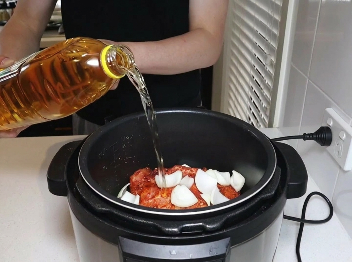 Apfelsaft wird aus einer Flasche in den Schnellkochtopf gegossen.