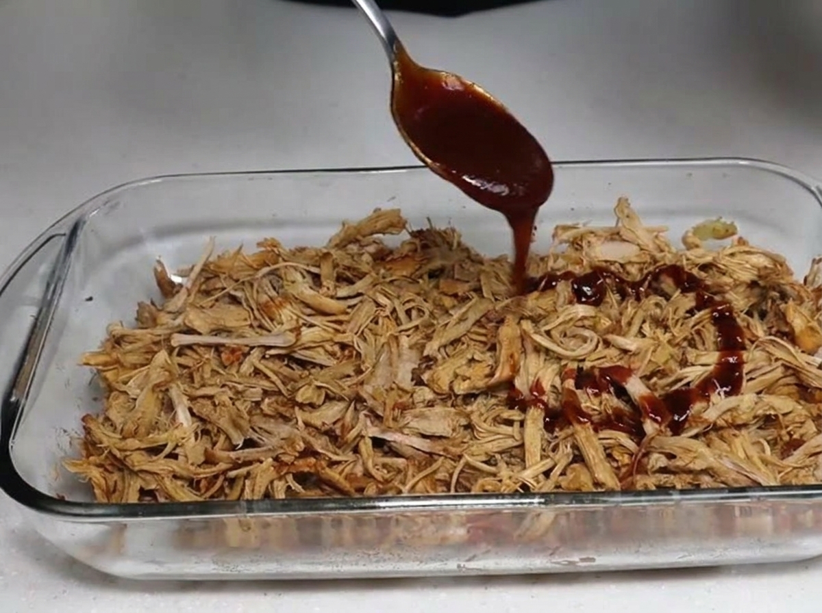 BBQ-Sauce wird über das zarte, geräucherte Fleisch geträufelt.