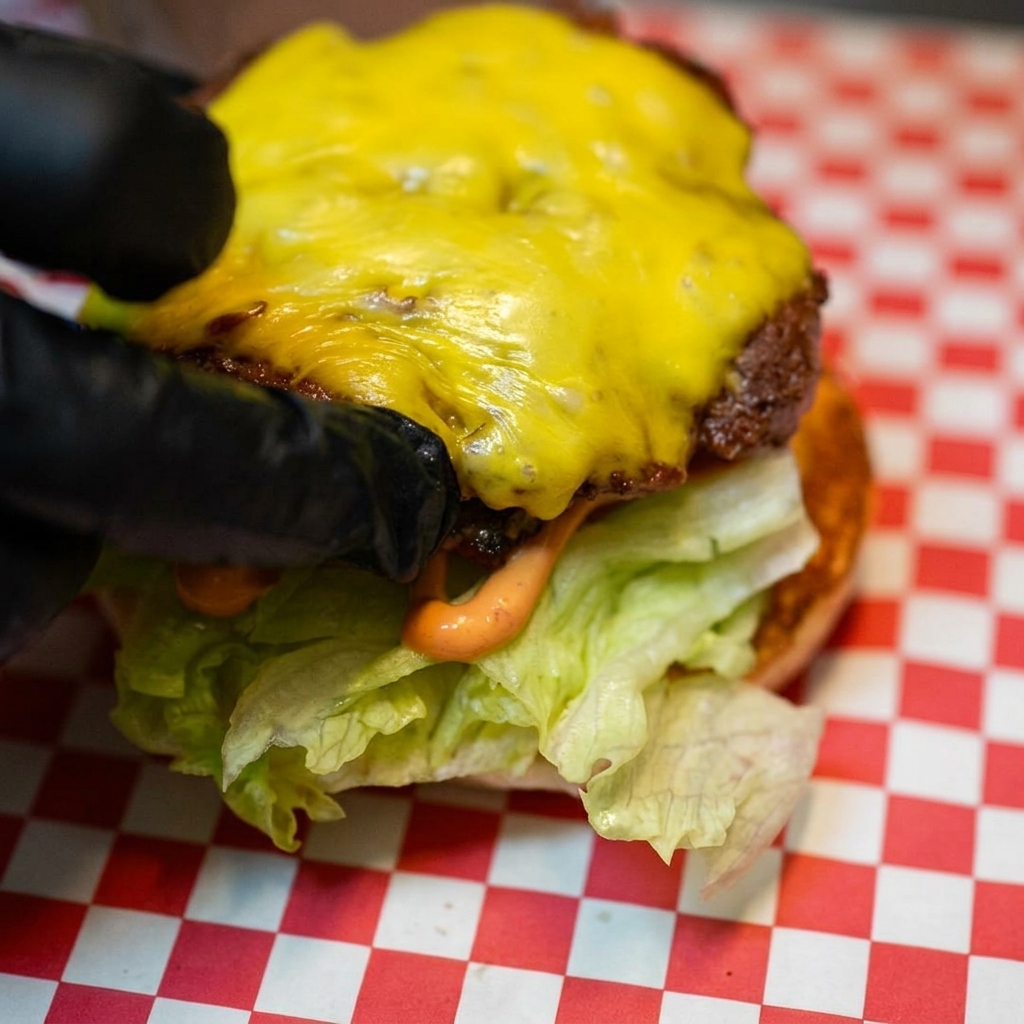 Das mit geschmolzenem Käse bedeckte Rindfleisch-Patty wird auf die Salat- und Tomatenbasis gelegt.