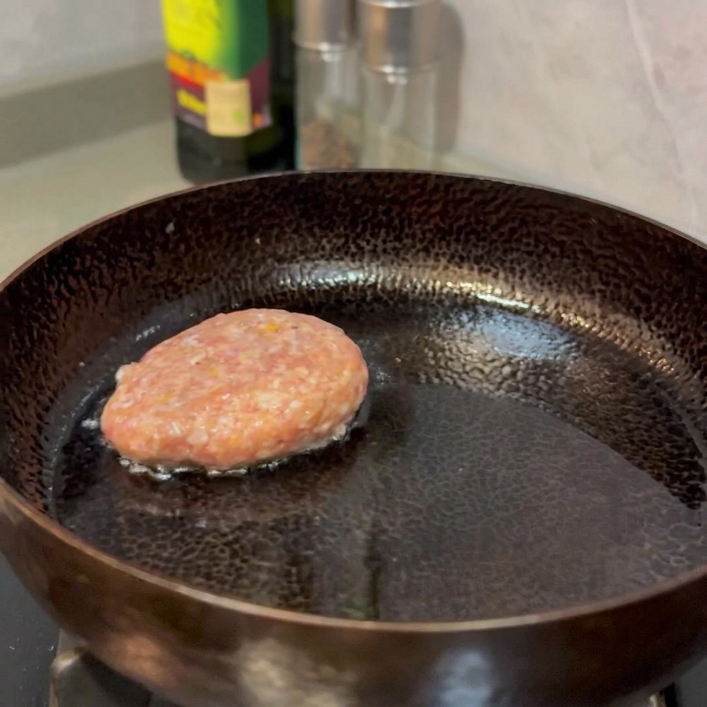 Rindfleisch-Pattys braten in einer Pfanne, bis sie goldbraun und fest sind.