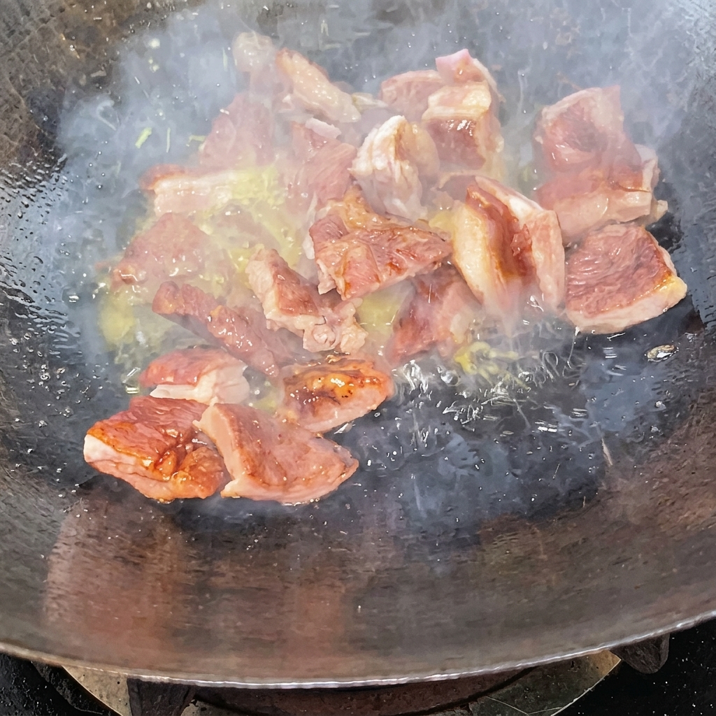 Rippchenstücke werden in einem Wok, überzogen mit einer dunklen Karamellglasur, pfannengerührt.