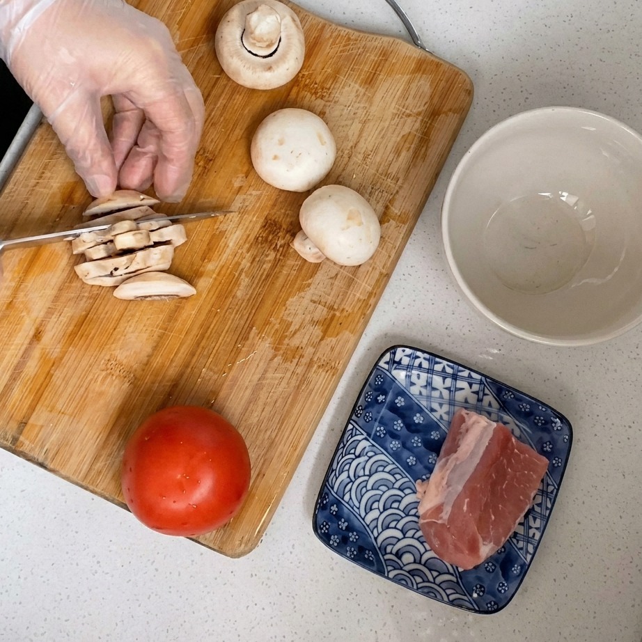 Frische weiße Champignons werden auf einem Holzbrett in dünne Scheiben geschnitten.