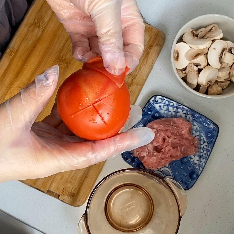 Die Schale wird von einer blanchierten, eingeritzten Tomate abgezogen.
