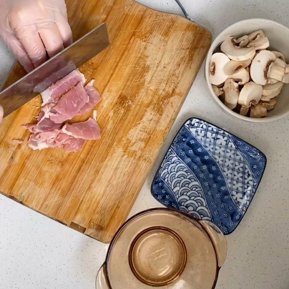 Rohes Schweinefleisch wird auf einem Holzbrett zu feinem Hackfleisch zerkleinert.