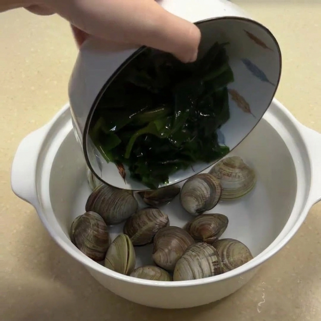 Eingeweichte Algen und Ingwerstreifen werden zu den Muscheln in die Schüssel gegeben.