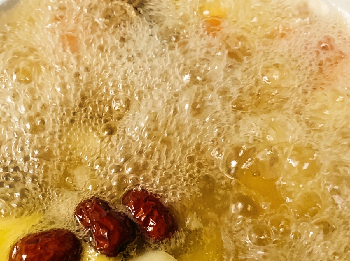 Rote Datteln und Gewürze werden in einen Topf mit blubbernder Hühnersuppe gegeben.
