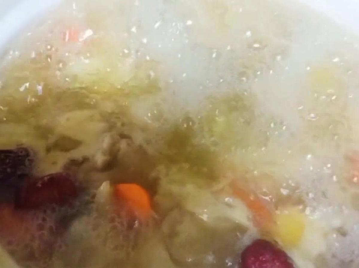 Szechuanpfefferkörner werden zum köchelnden Hähnchen- und Gemüseeintopf gegeben.
