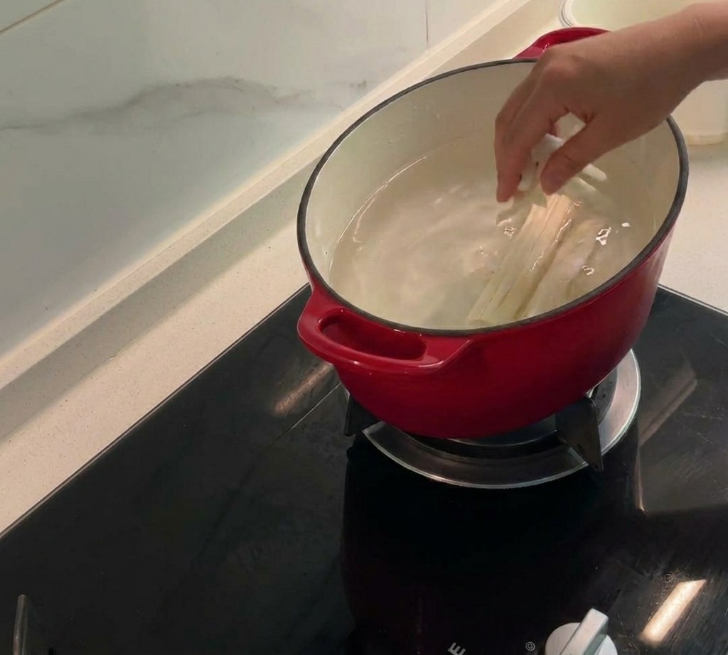 Maisfäden, Kolben und Hähnchenhaut köcheln in einem Topf mit Wasser, um eine würzige Brühe zu bilden.
