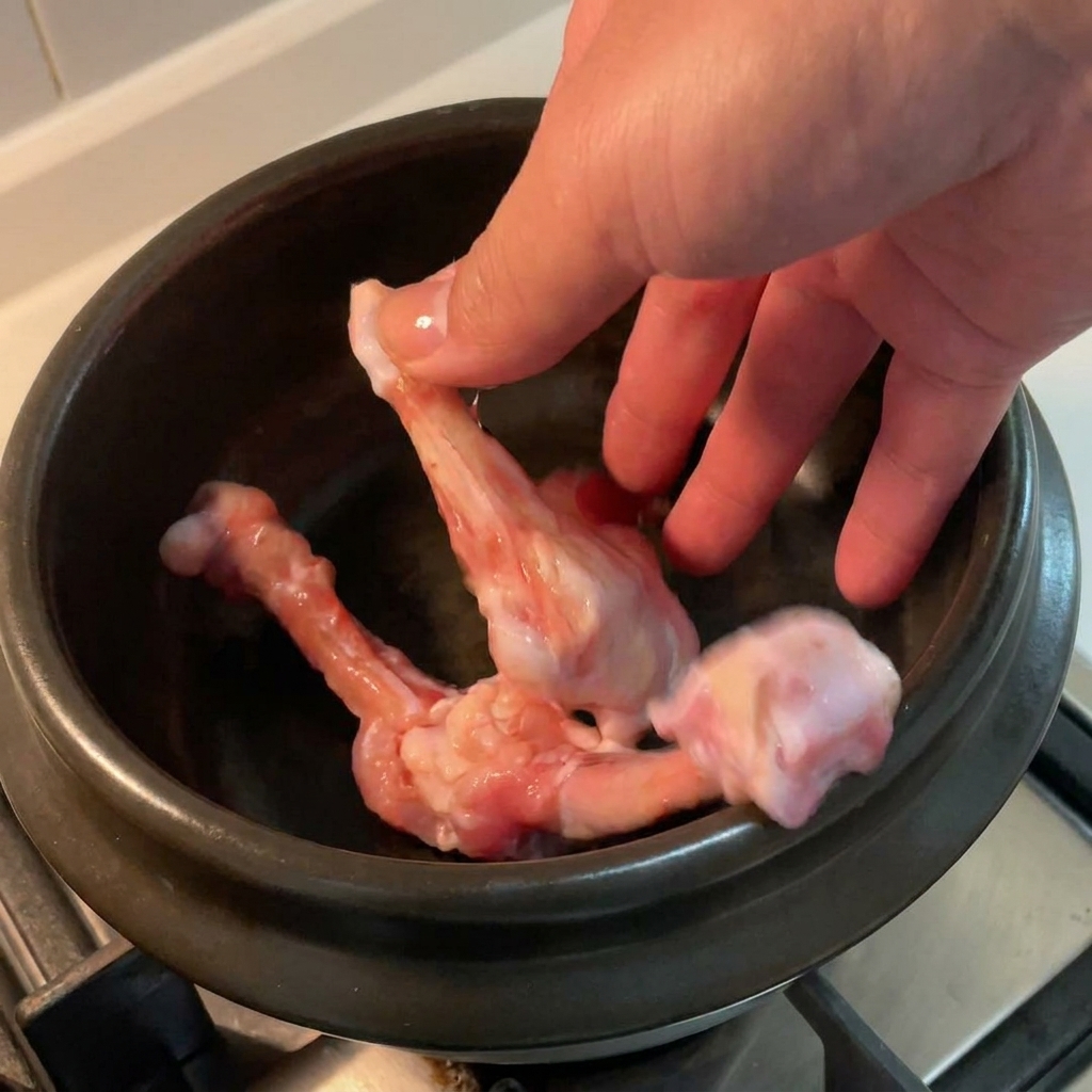 Rohe Hähnchenknochen werden in einem schwarzen Keramiktopf angerichtet.
