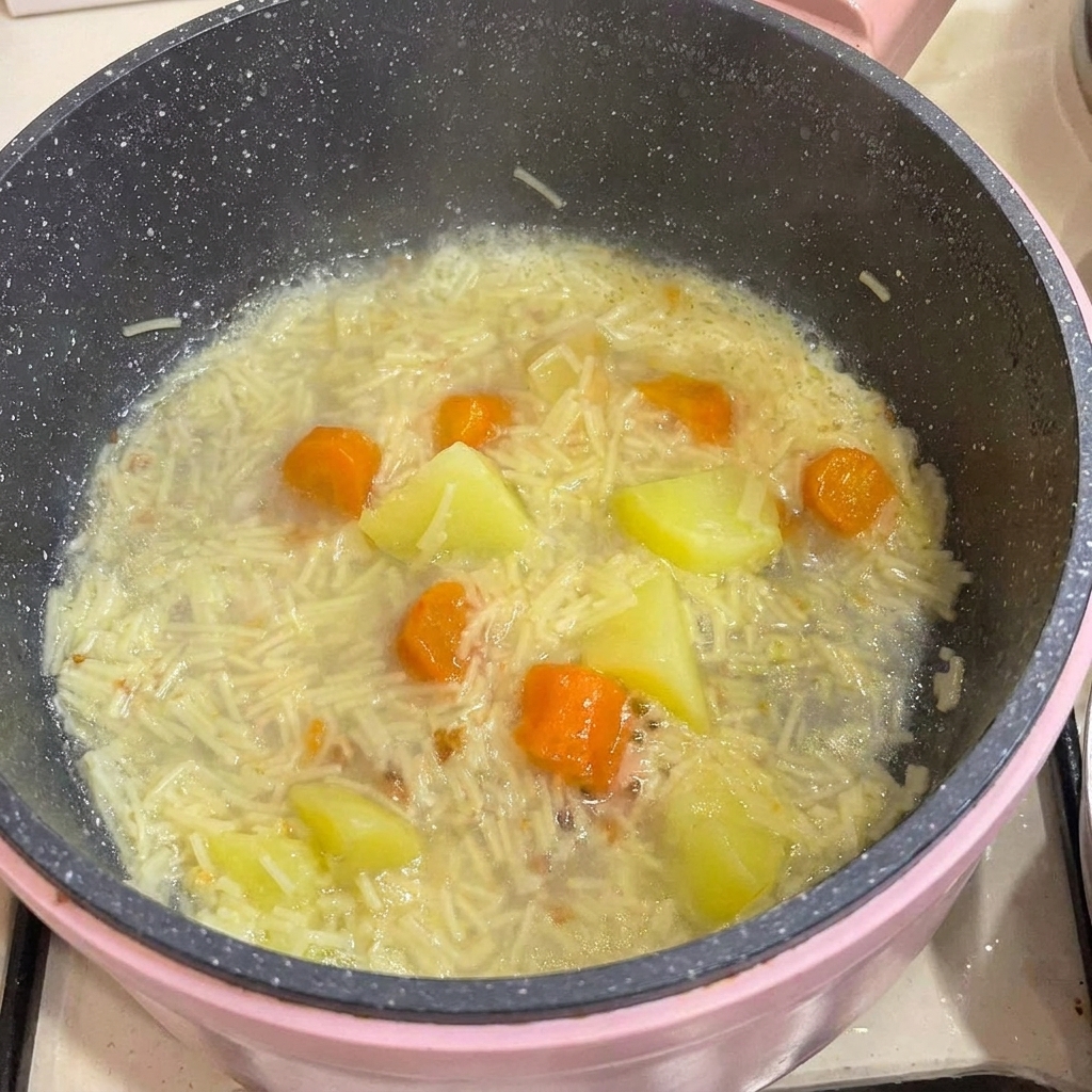 Das vom Knochen gelöste Hühnerfleisch wird zurück in den Topf mit Nudeln, Kartoffeln und Gemüse gegeben.