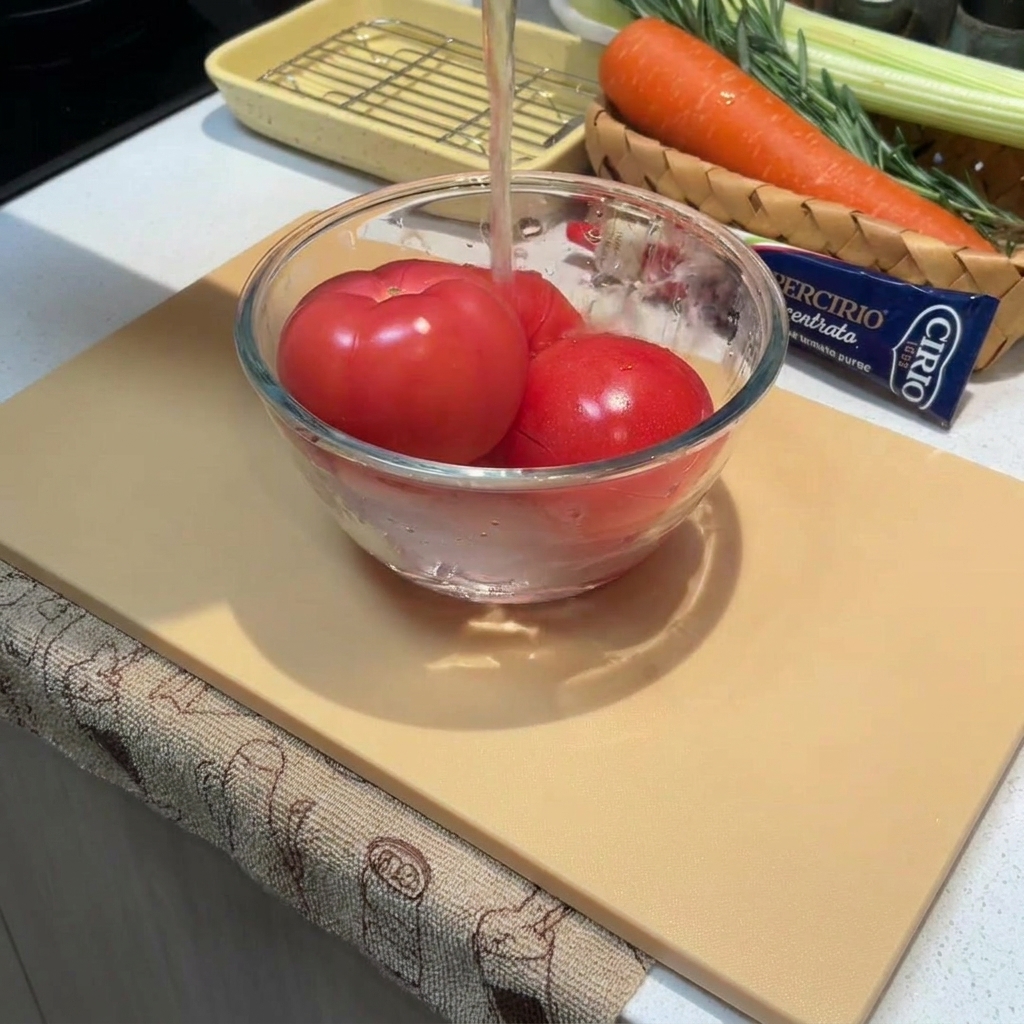 Nahaufnahme von ganzen Tomaten in einer Schüssel, die mit heißem Wasser übergossen werden.