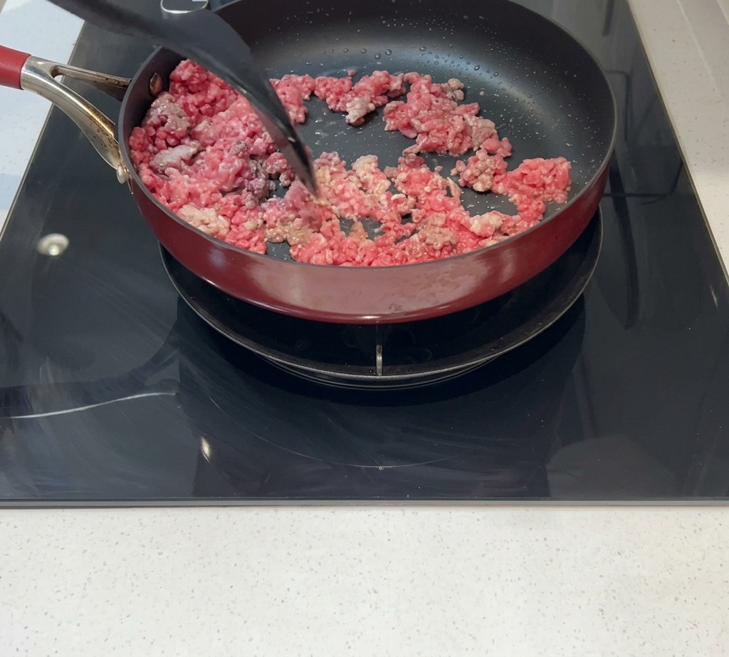 Hackfleisch wird in einer Pfanne gerührt, bis es gebräunt und gar ist.
