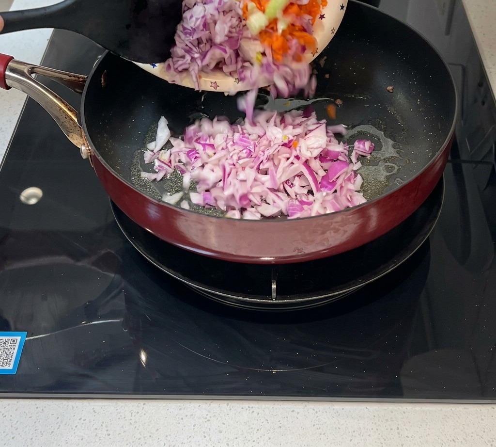 Fein gewürfelte Zwiebeln, Karotten und Sellerie werden zum Anbraten in eine Pfanne gegeben.