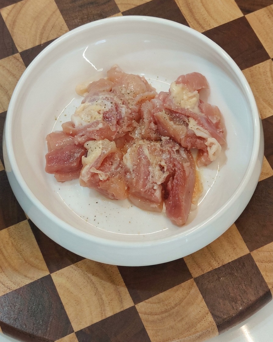 Schüssel mit gewürzten, rohen Hähnchenstücken.