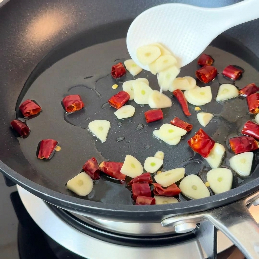 Knoblauch und Chilistücke braten in einer heißen Pfanne mit Öl.