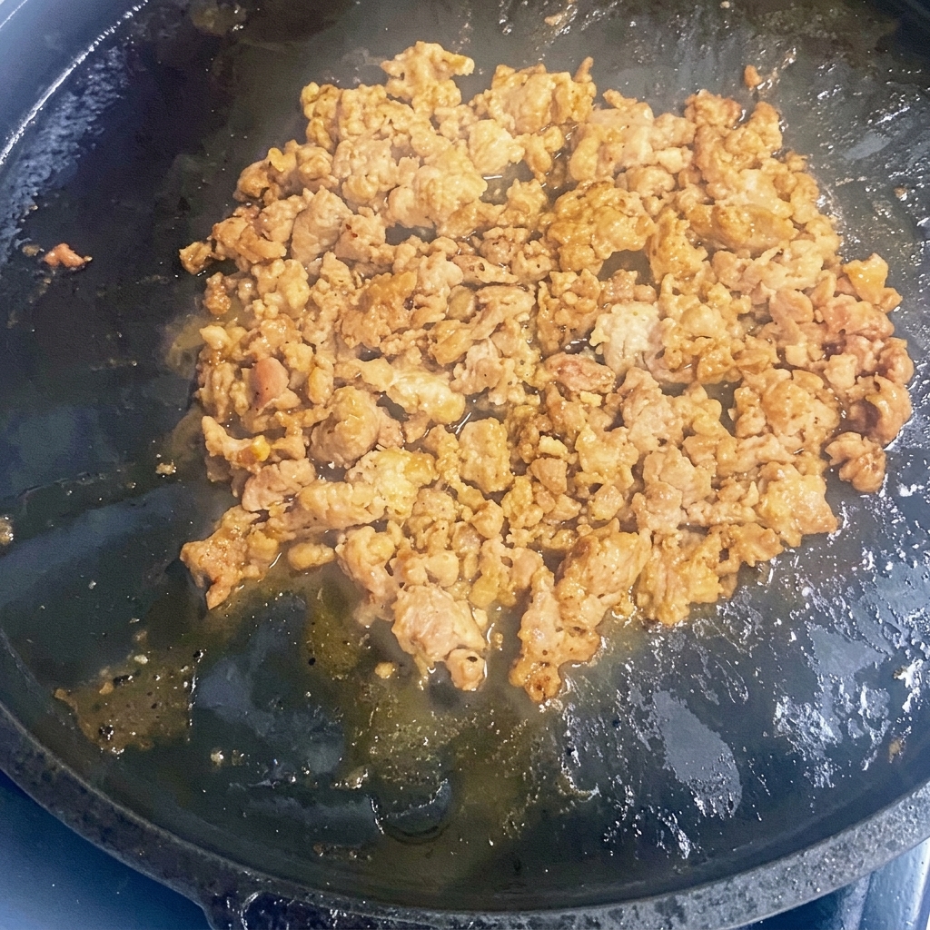 Hackfleisch wird in einer heißen gusseisernen Pfanne angebraten.