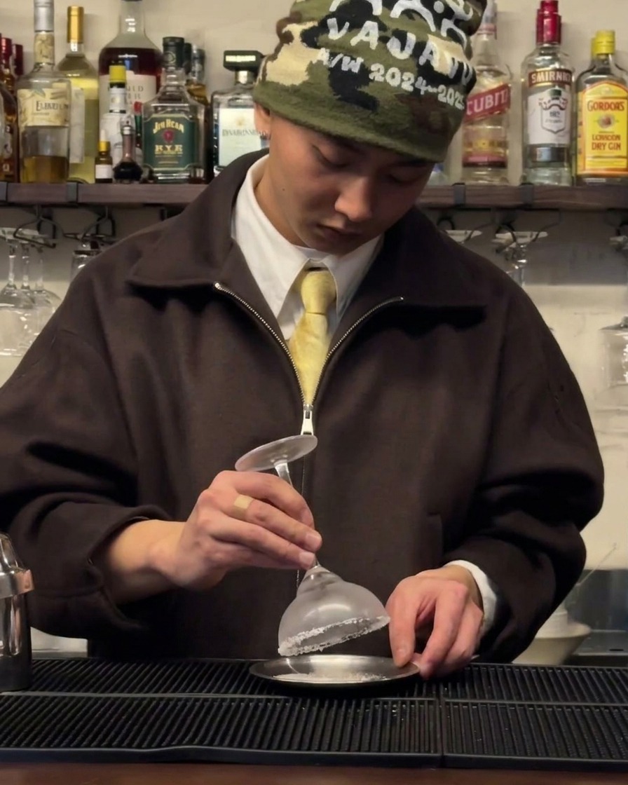 Ein gekühltes Cocktailglas, das auf einer kleinen Untertasse mit einem Salzrand versehen wird.