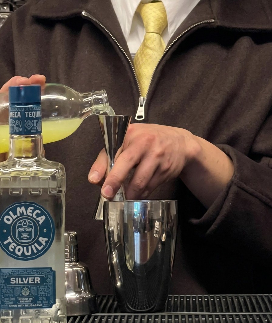 Frischer Limettensaft, der über einem Cocktailshaker in einen Jigger gegossen wird.