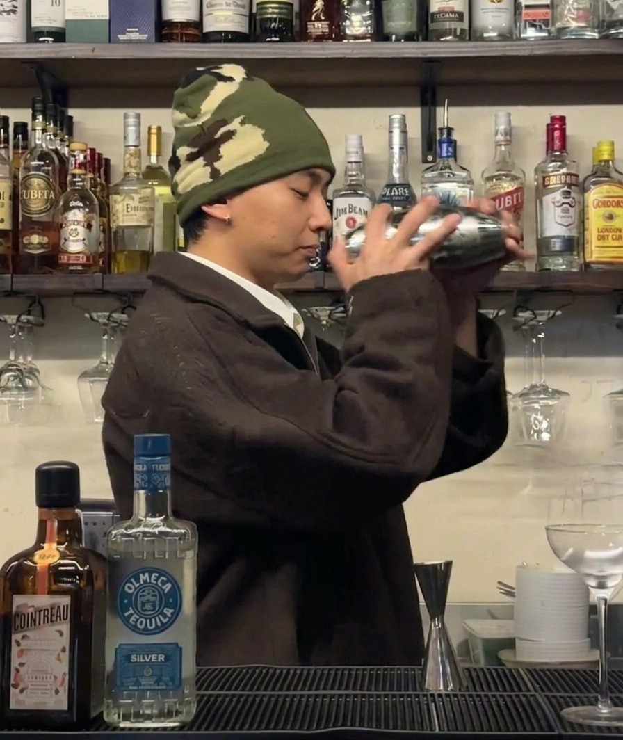 Ein Barkeeper, der einen Cocktailshaker kräftig schüttelt, um die Zutaten zu kühlen.
