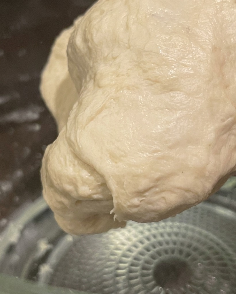 Ein glatter, elastischer Teigball, handgeknetet und bereit für die Gärung.