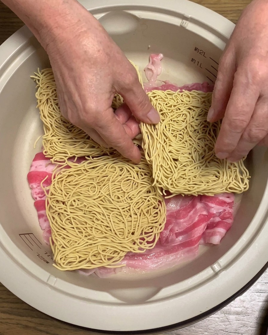 Trockene Ramen-Nudelblöcke, die auf den Schweinebauch im Topf geschichtet werden.