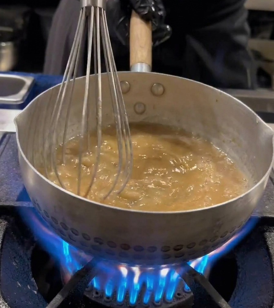 Ramen-Nudeln werden mit einem Schneebesen in kochendem Wasser bewegt.