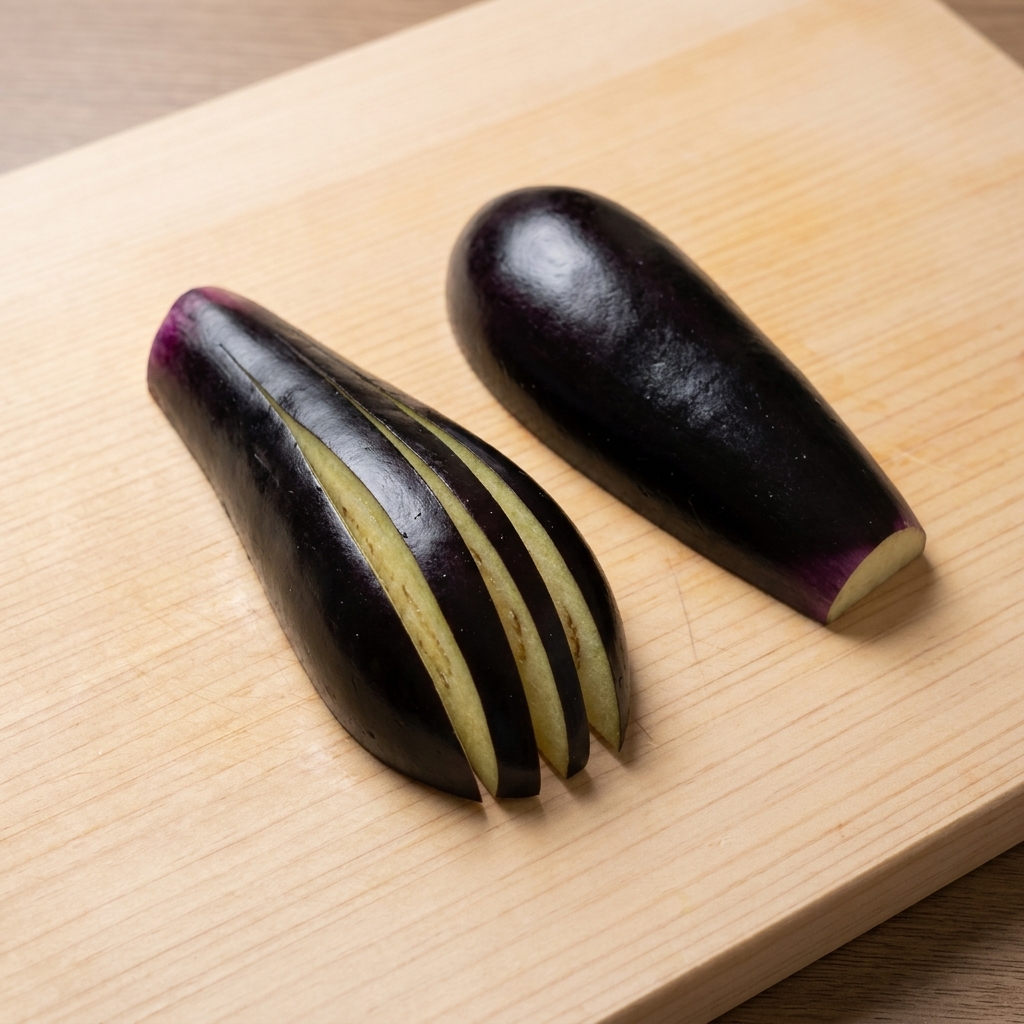 Aubergine wird auf einem Schneidebrett fächerförmig eingeschnitten.
