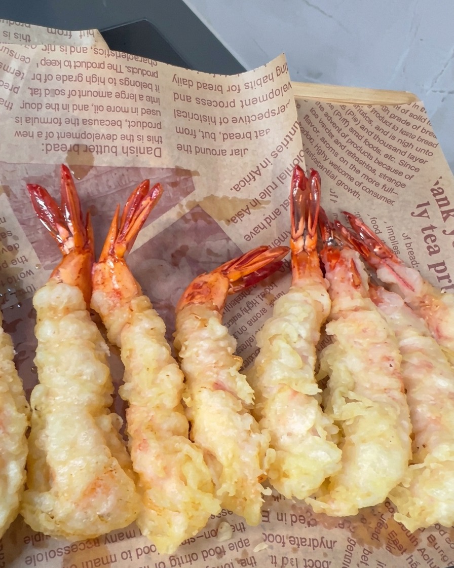 Bierteig-Garnelen frittieren im heißen Öl, wobei sich kleine knusprige Spitzen auf der Oberfläche bilden.