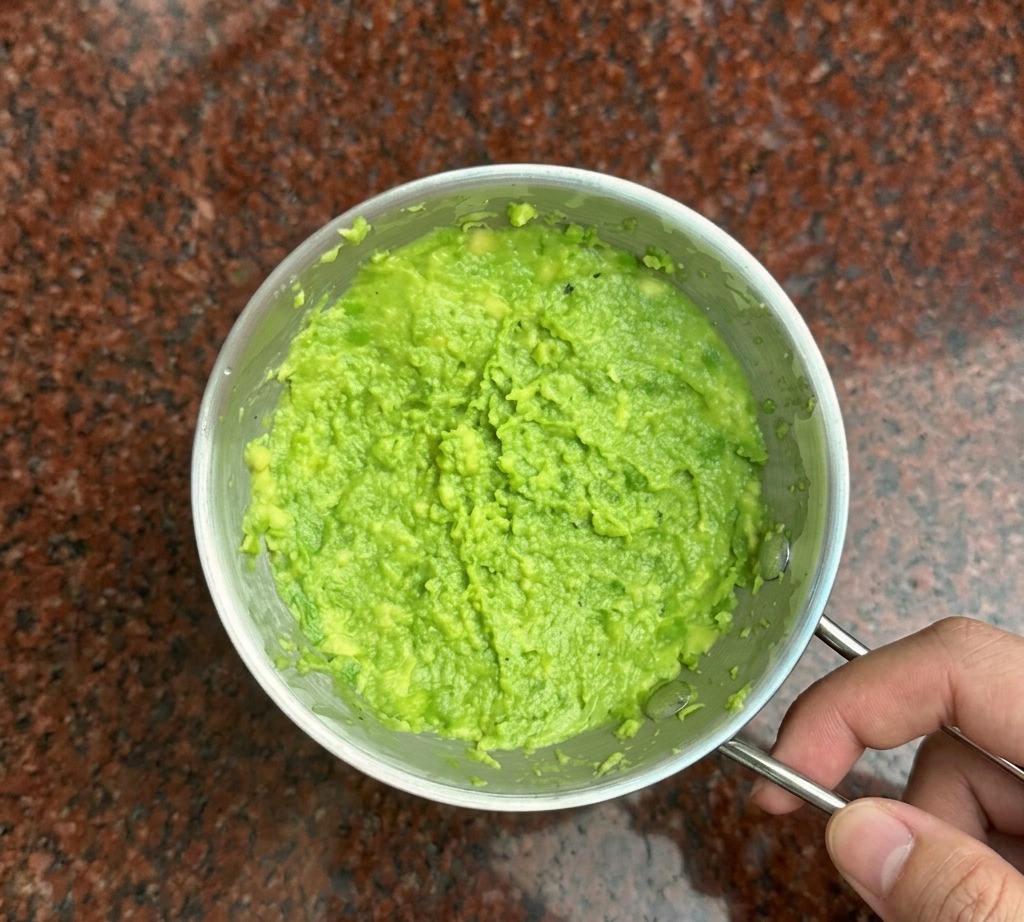 Eine Metallgabel zerdrückt hellgrenze Avocado zu einer dicken Paste in einer kleinen Schüssel.