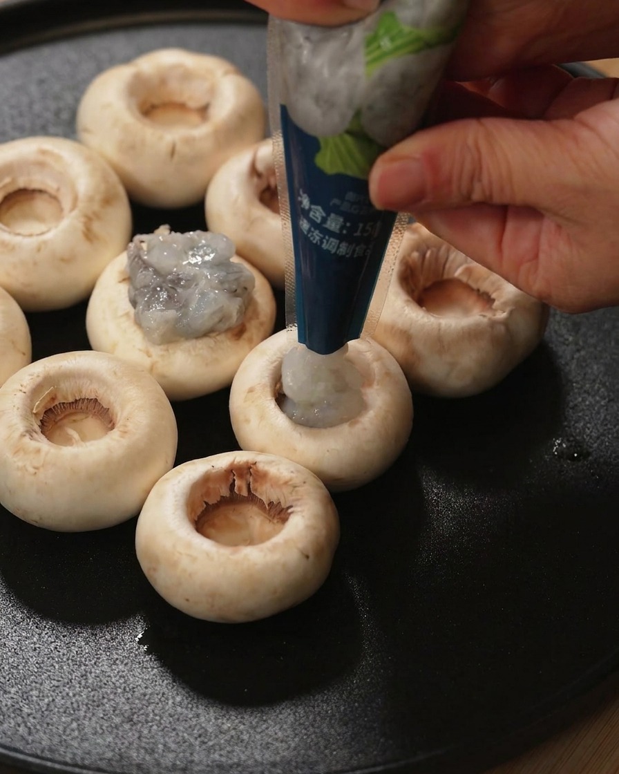 Ein Pilzkopf ohne Stiel, der direkt mit einer Portion roher Garnelenpaste gefüllt wird