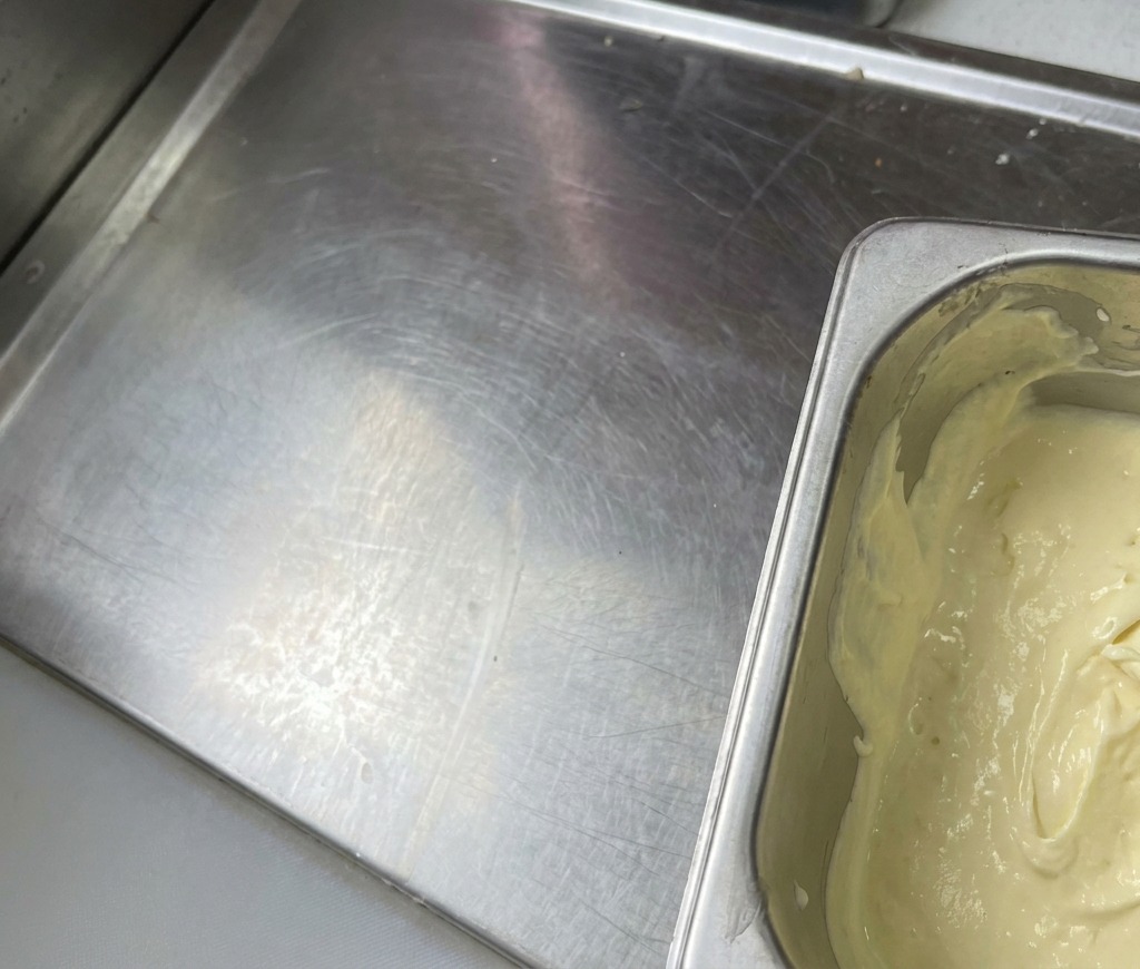 Ein Metallbehälter, gefüllt mit einer dicken, hellgelben Sauce, die glatt und cremig aussieht.