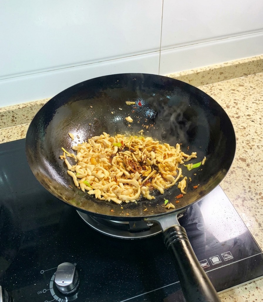 Hähnchenfleisch im Wok wird mit Sojasauce und einer Portion dickflüssiger Austernsauce vermengt.