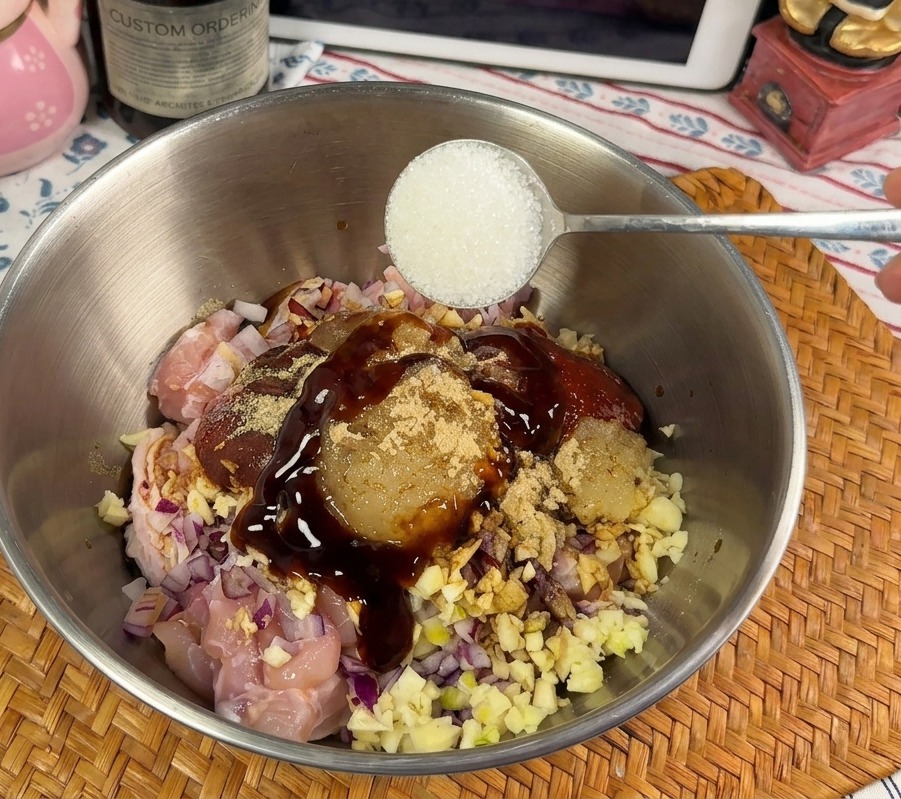 Ein Löffel weißer Zucker wird zu der dicken, roten Hähnchenmarinade gegeben.
