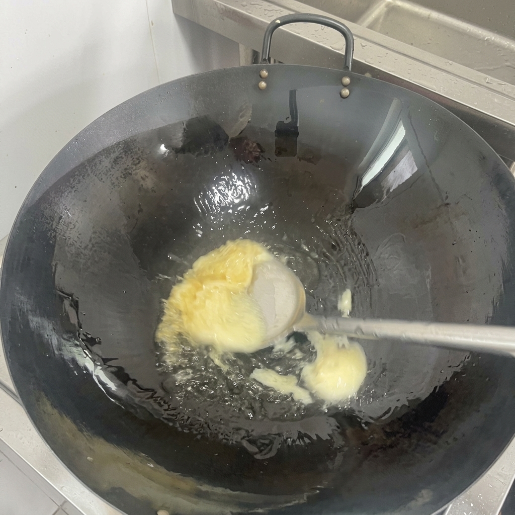 Ein festes Stück weißer Schweineschmalz schmilzt zu klarem Öl auf dem Boden eines eingebrannten schwarzen Woks.