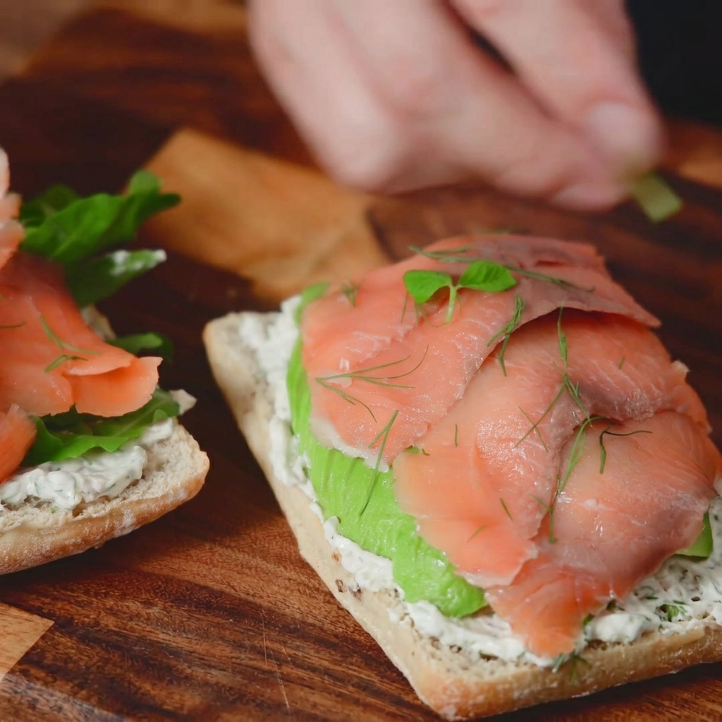 Eine Makroaufnahme von frischen Dillzweigen und winzigem Mikrogrün, die als Garnierung auf ein Räucherlachs-Sandwich gestreut werden.