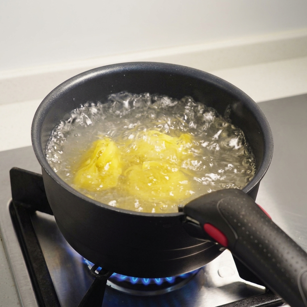Fettuccine-Nudeln kochen in kochendem, gesalzenem Wasser in einem dunklen Topf auf einem Gasherd.