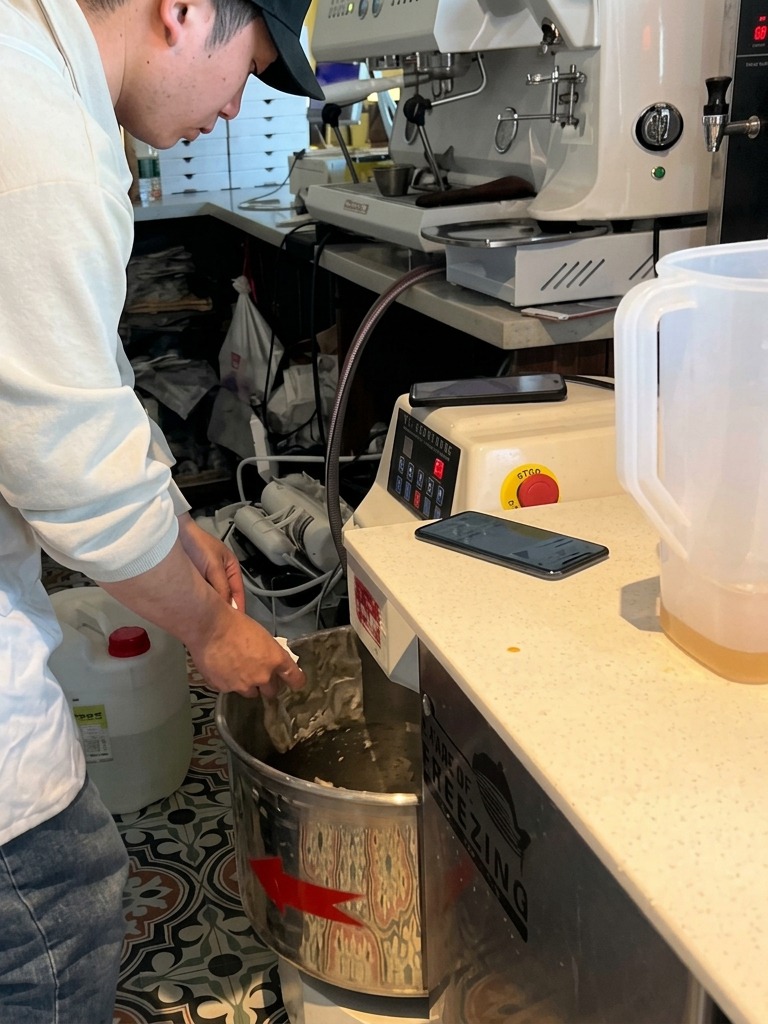 Ein Bäcker gibt Hefe in eine große Knetmaschine, in der der Teig beginnt, Klumpen zu bilden.