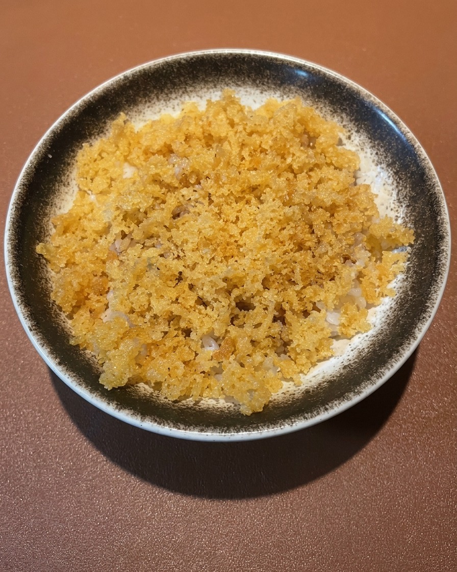 Eine Schale Reis, belegt mit goldenem, knusprigem Garnelen- und Gemüsetempura.