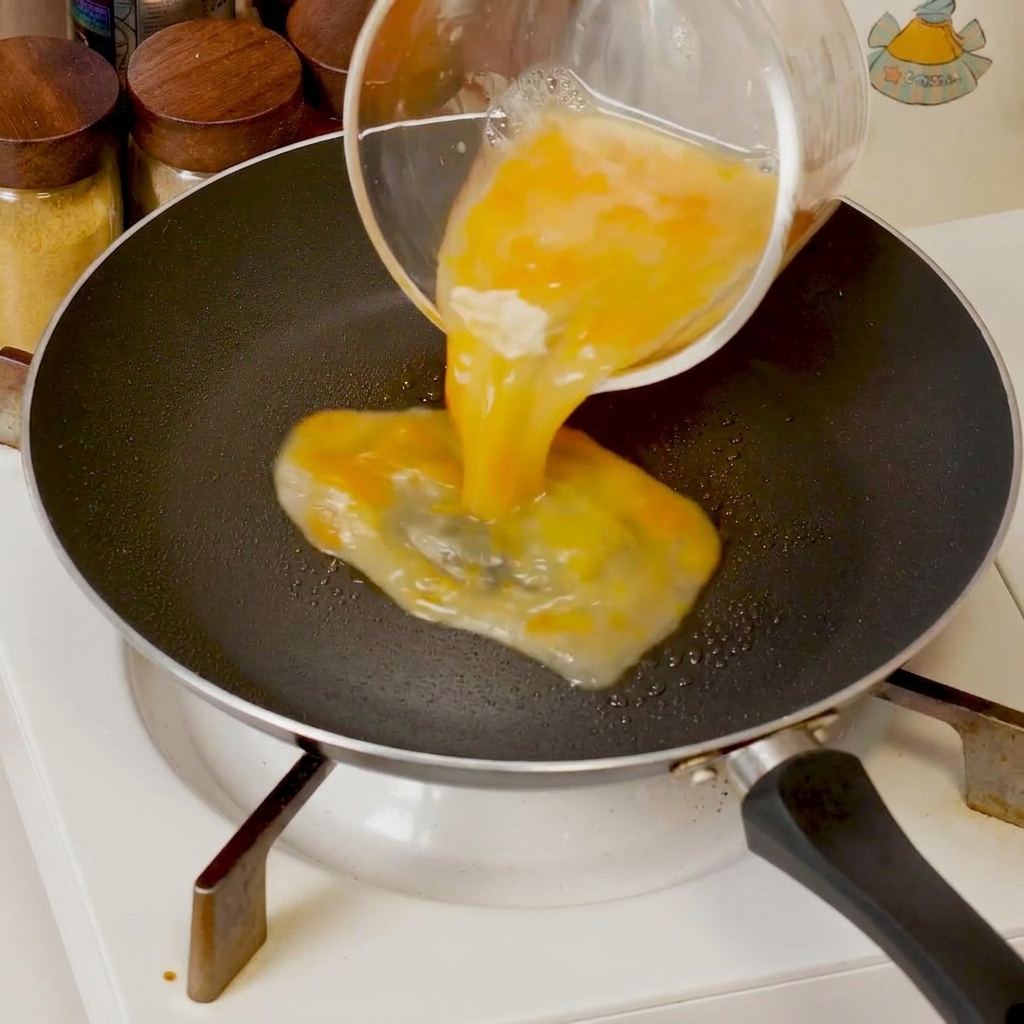 Verquirlte Eier garen in einer Pfanne und werden mit einem Spatel zur Mitte geschoben, um weiche Klümpchen zu bilden.